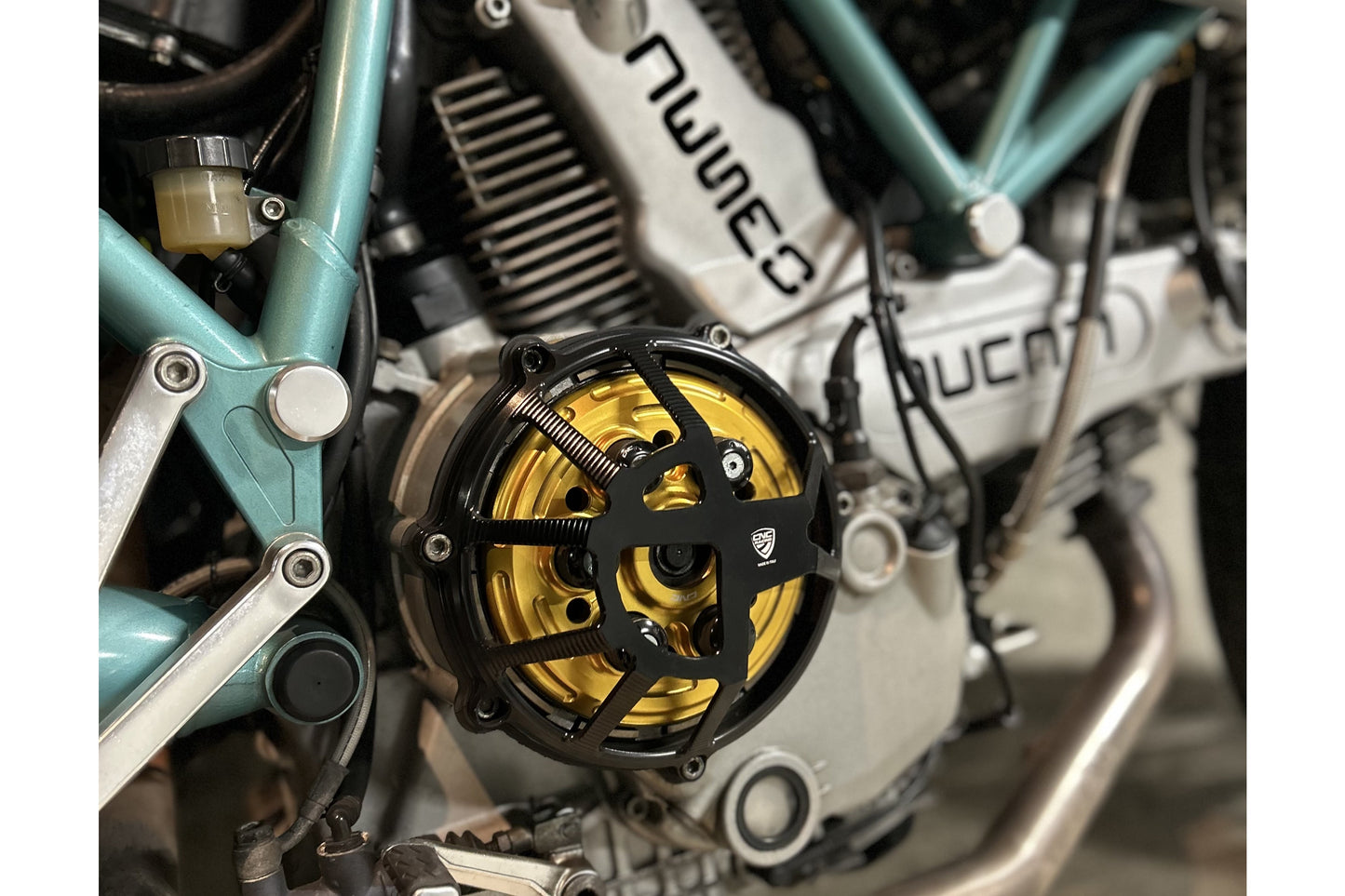 Koppelingsdeksel Traffic Ducati Supersport 750 (1999-2002) zijaanzicht in zwart met gouden drukplaat en zwarte veren plus schotels